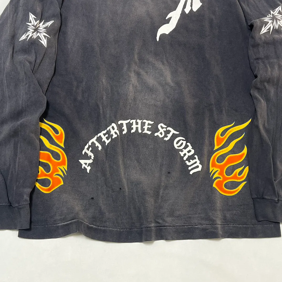 SAINT Mxxxxxx M/AFTER LS_TEE/BLACK Flame arrow Letter M retro distressed long tee Washed black S-XL Tubular fabric Assute ready-made garments dyed The whole piece is sprayed with horse-hair spray and then sprayed again to fade the color. The collar and cuffs are frayed. Many places are frayed. Extra large printing position. Very difficult to print. Complete accessories. With little angel anti-counterfeiting label.